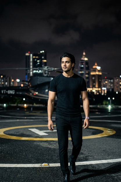 Man in black clothing standing on a helipad with city skyline in the background