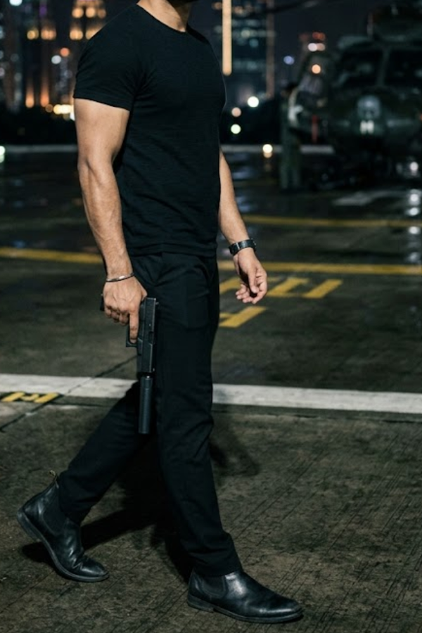 Person in black clothing holding a gun on a dark street at night. Flemingway Pure Midnight